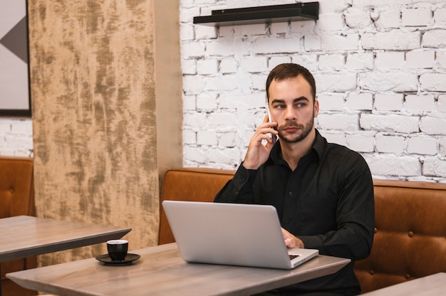 Businessman talking on cell phone in cafe