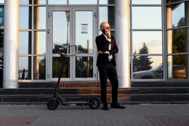 Businessman talking on the phone next to the electric scooter