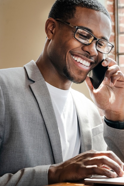 Businessman talking on a phone while using a laptop