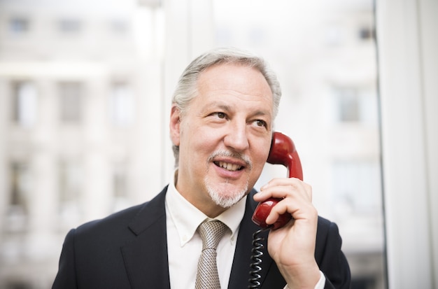 Businessman talking on a vintage phone in his office