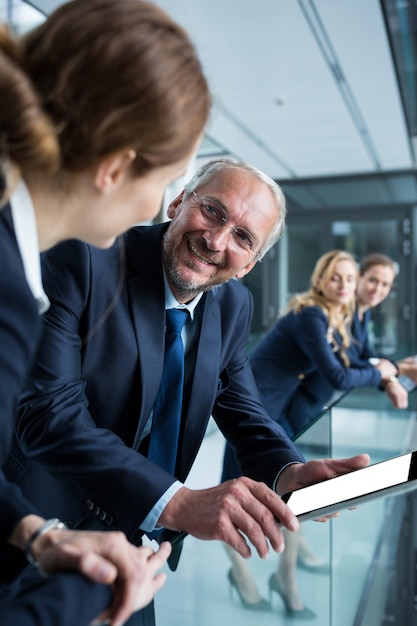 Businessman talking with colleague while holding digital tablet