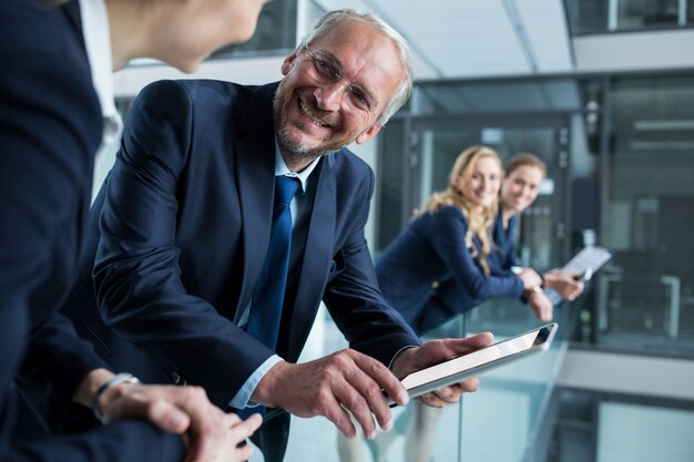 Businessman talking with colleague while holding digital tablet