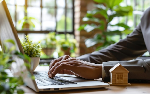 Photo businessman typing on a laptop in a green office environment with a wooden house model