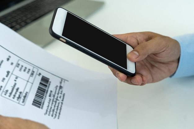 Businessman uses a smartphone to scan the barcode to pay monthly phone bills after receiving an invoice sent to office Online bill payment concept