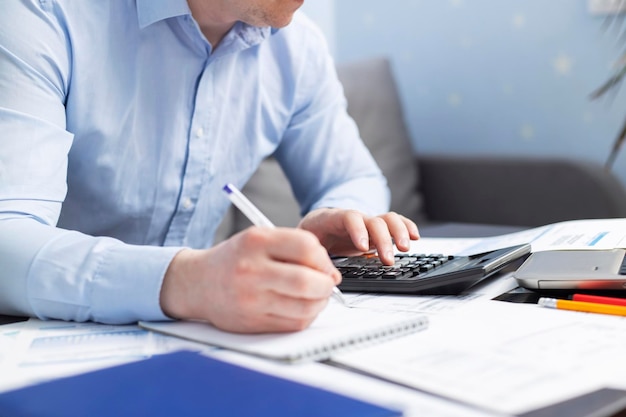 Businessman using calculator to calculate bills at the table in office