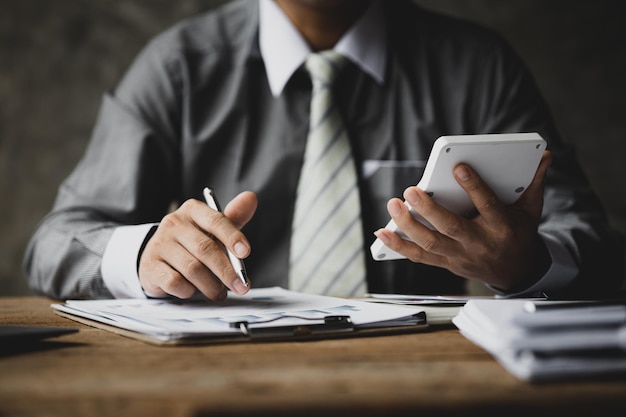 Businessman using a calculator to calculate numbers on a company's financial documents he is analyzing historical financial data to plan how to grow the company Financial concept