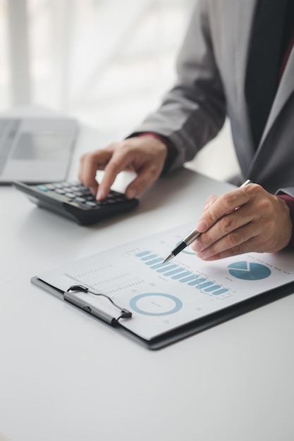 Businessman using a calculator to calculate numbers on a company's financial documents she is analyzing historical financial data to plan how to grow the company Financial concept