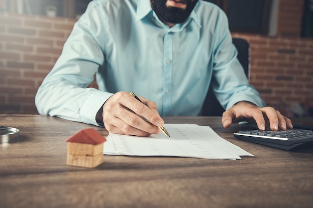 Businessman using calculator and  house model in office desk