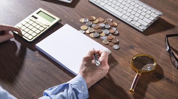 Businessman using calculator and writes in notepad