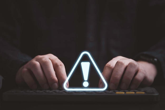 Businessman using computer laptop with triangle caution warning sign for notification error and maintenance concept