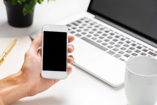 Businessman using his smartphone with blank screen in an office close up