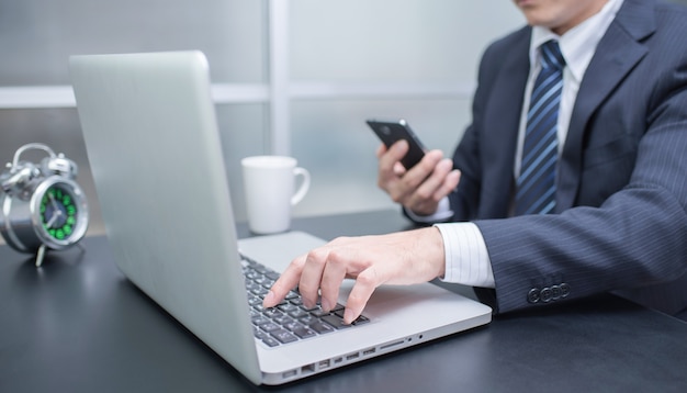 Businessman using laptop and mobile phone