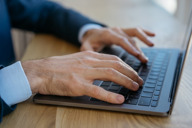 Businessman using laptop, typing, searching information, sitting in office. Freelancer working from home