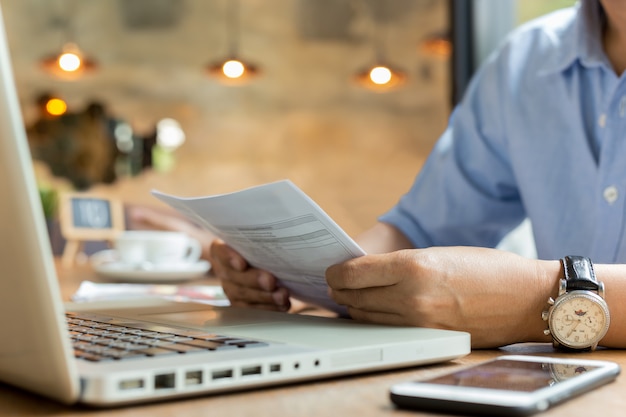 Businessman using laptop while looking at invoice.