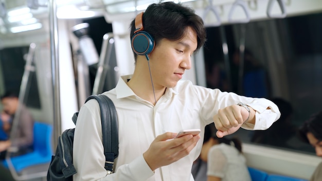 Businessman using mobile phone on public train . Urban city lifestyle commuting concept .