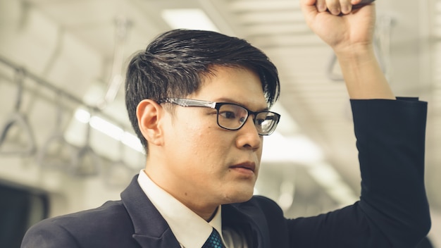 Businessman using mobile phone on public train . Urban city lifestyle commuting concept .