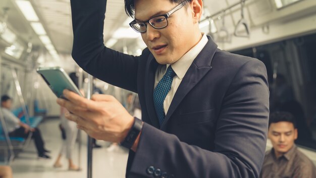 Businessman using mobile phone on public train 