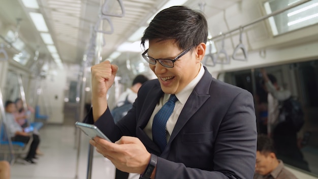 Businessman using mobile phone on public train