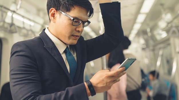 Businessman using mobile phone on public train