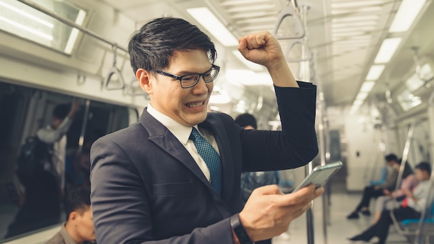 Businessman using mobile phone on public train