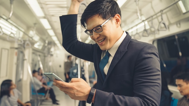 Businessman using mobile phone on public train