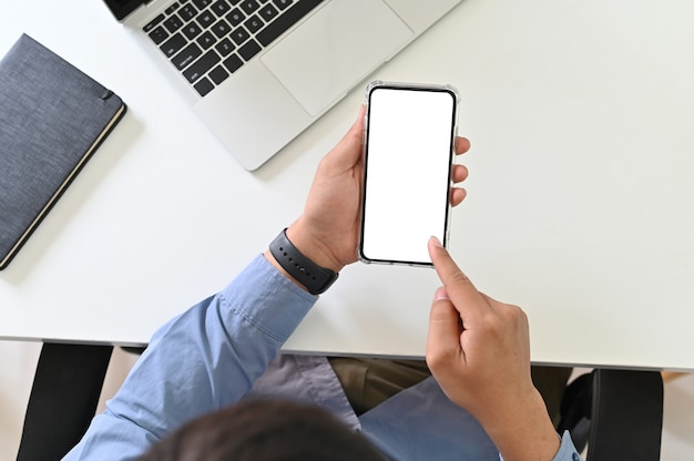 Businessman using mockup smartphone on office desk, clipping path display screen.