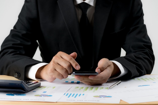 Businessman using smartphone over the desk with document paper at the office.