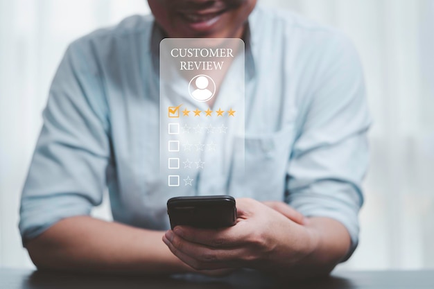 Businessman using smartphone for select smiley face icon for client evaluation and customer satisfaction after use product and service concept