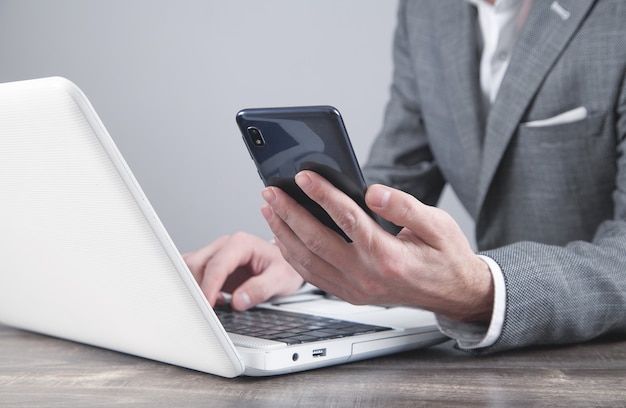 Businessman using smartphone and working on laptop.