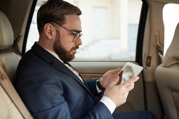 Businessman using tablet pc in the car