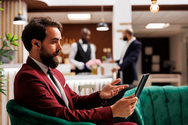 Photo businessman on videocall meeting using tablet for internet connection while he waits for check in process. entrepreneur on business trip travelling abroad, remote teleconference.