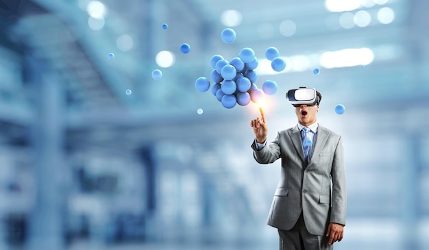 Businessman in VR headset with abstract bunch of spheres. Mixed media