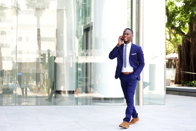 Businessman walking in the city using mobile phone 