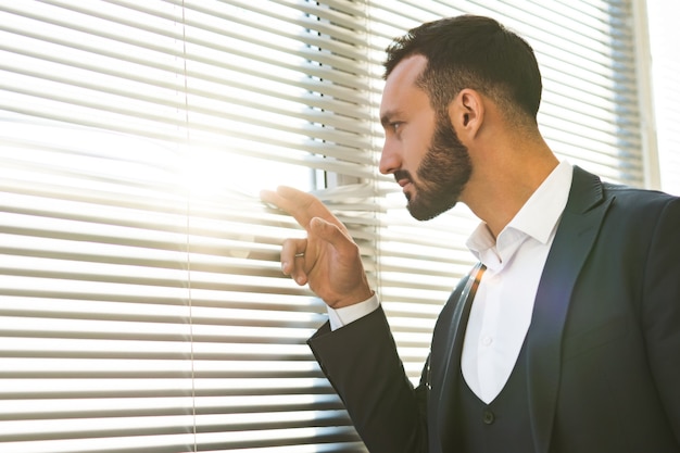 The businessman watching through the blinds