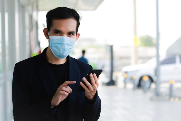 Businessman wear face mask use smartphone in lifestyle and then mask to protect coronavirus covid19