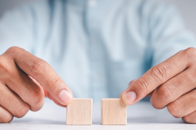 Businessman wearing a blue shirt arranging the empty wooden blocks with his hands Which is placed on a white wooden table Business strategy and action plan Copy space