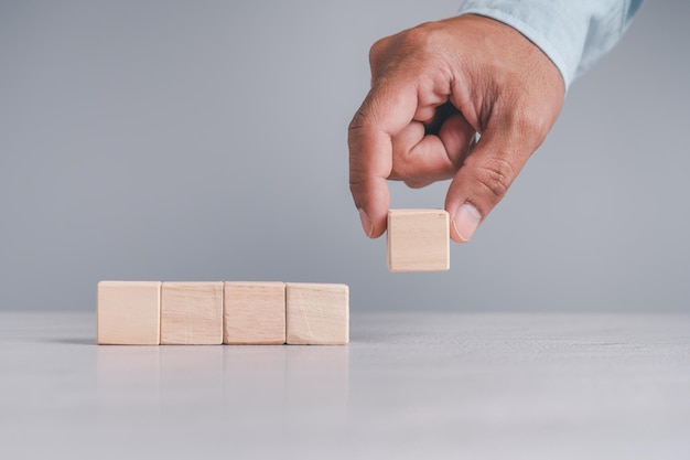 Businessman wearing a blue shirt arranging the empty wooden blocks with his hands Which is placed on a white wooden table Business strategy and action plan Copy space