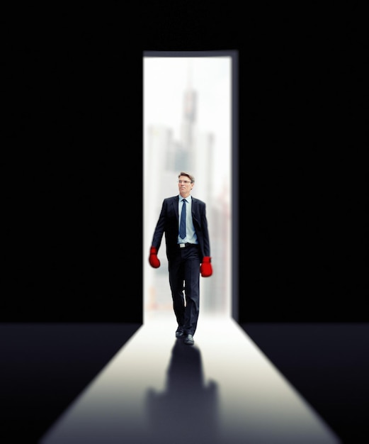 Businessman wearing boxing gloves while walking on floor