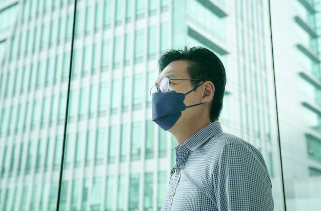 Businessman wearing face mask with office building at the background