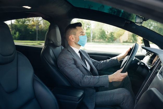 businessman wearing medical mask in prevention for coronavirus and driving his car to work