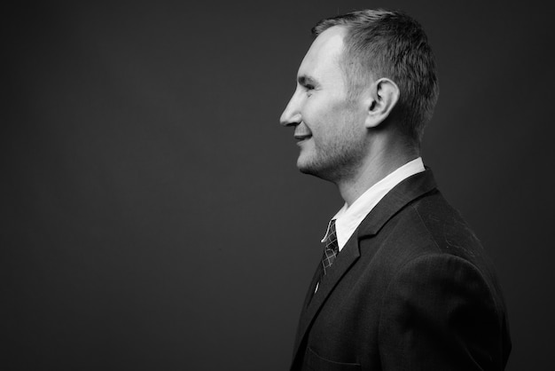 businessman wearing suit against gray wall in black and white