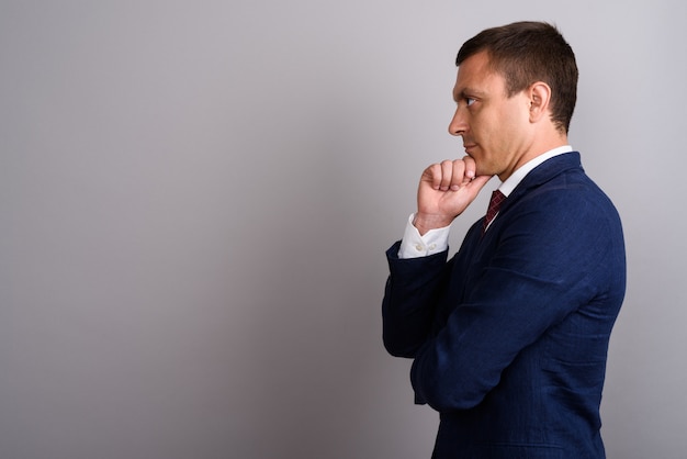 Businessman wearing suit against gray wall