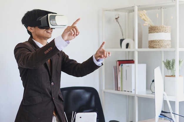 Businessman wearing suit and VR glasses is standing and pointing fingers in the office.