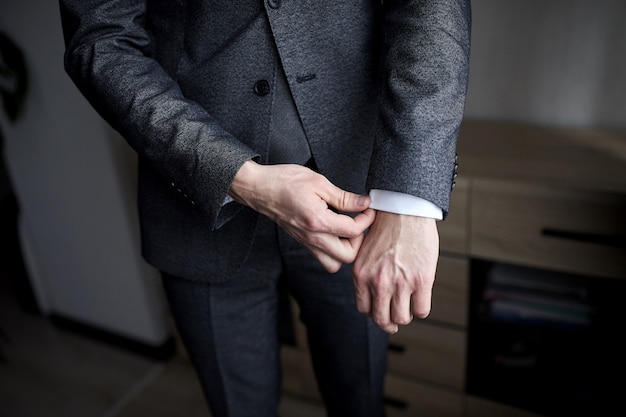 Businessman wears a jacket,male hands closeup,groom getting ready in the morning before wedding ceremony