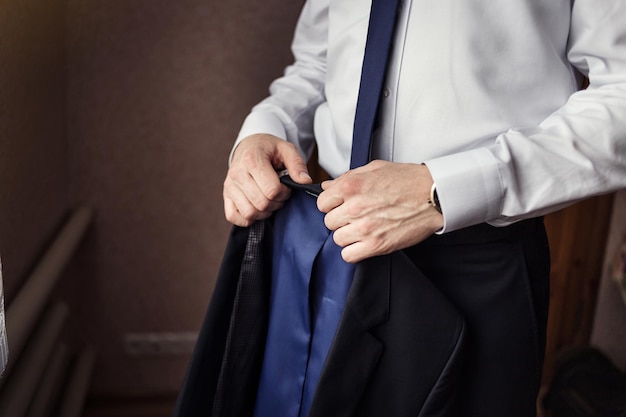 Businessman wears a jacketmale hands closeupgroom getting ready in the morning before wedding ceremony