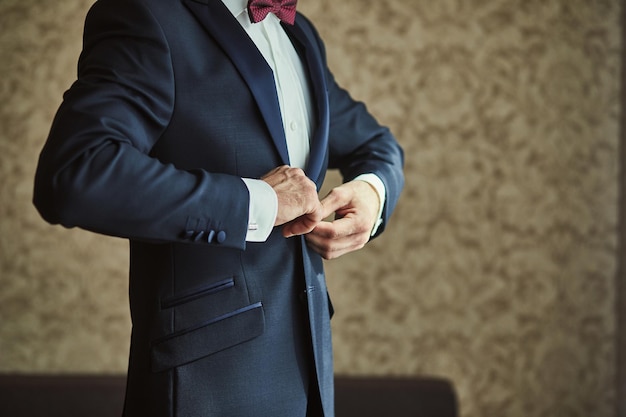 Businessman wears a jacketmale hands closeupgroom getting ready in the morning before wedding ceremony