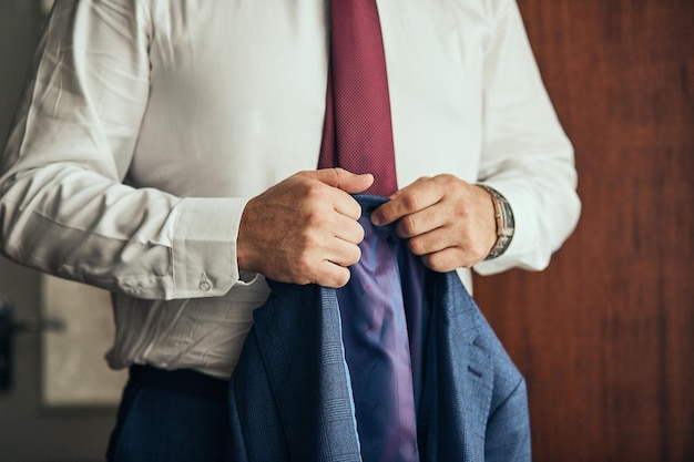 Businessman wears a jacketmale hands closeupgroom getting ready in the morning before wedding ceremony