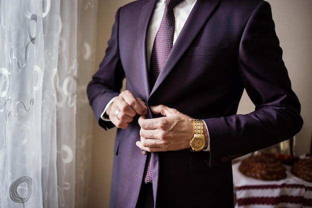 Businessman wears a jacketmale hands closeupgroom getting ready in the morning before wedding ceremony