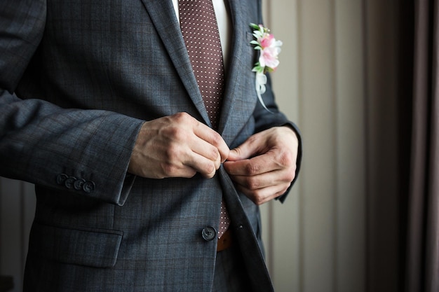 Businessman wears a jacketmale hands closeupgroom getting ready in the morning before wedding ceremony