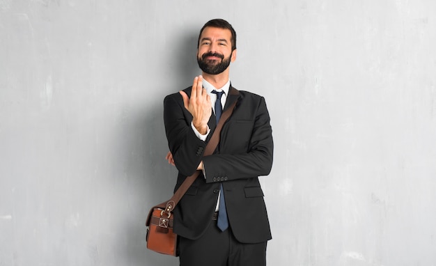 Businessman with beard inviting to come with hand. Happy that you came